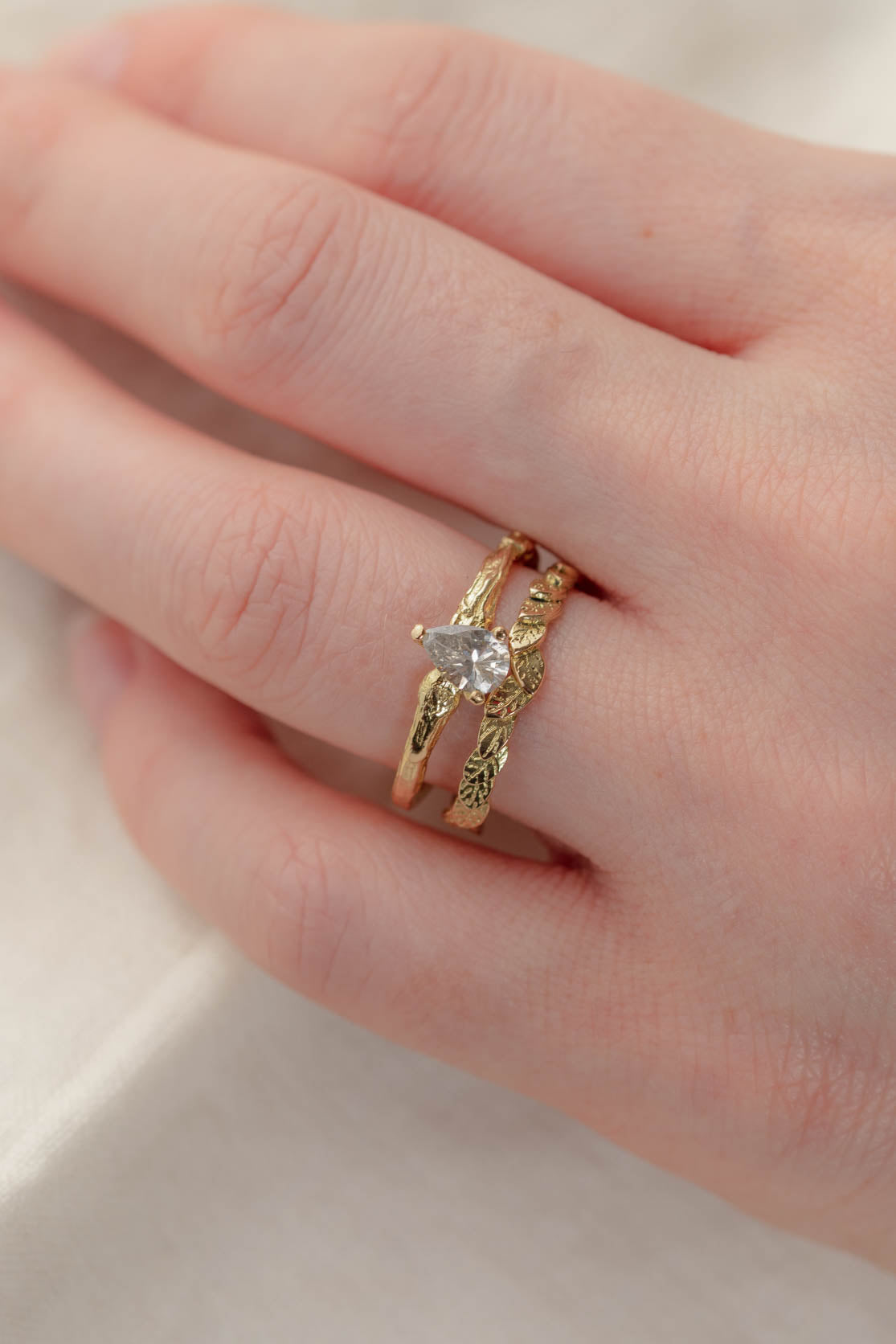 Handmade Solid Gold Twig Ring With Pear Shaped Diamond worn as an alternative handmade engagement ring, stacked with our leaf wedding ring.