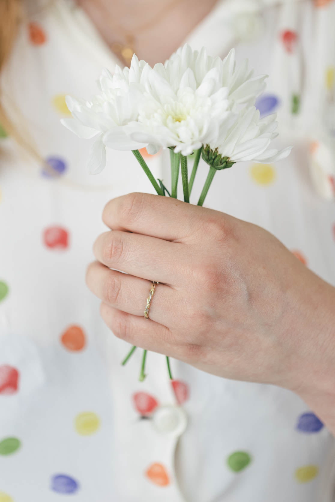 double twisted twig ring in 18ct gold being worn by a woman holding flowers