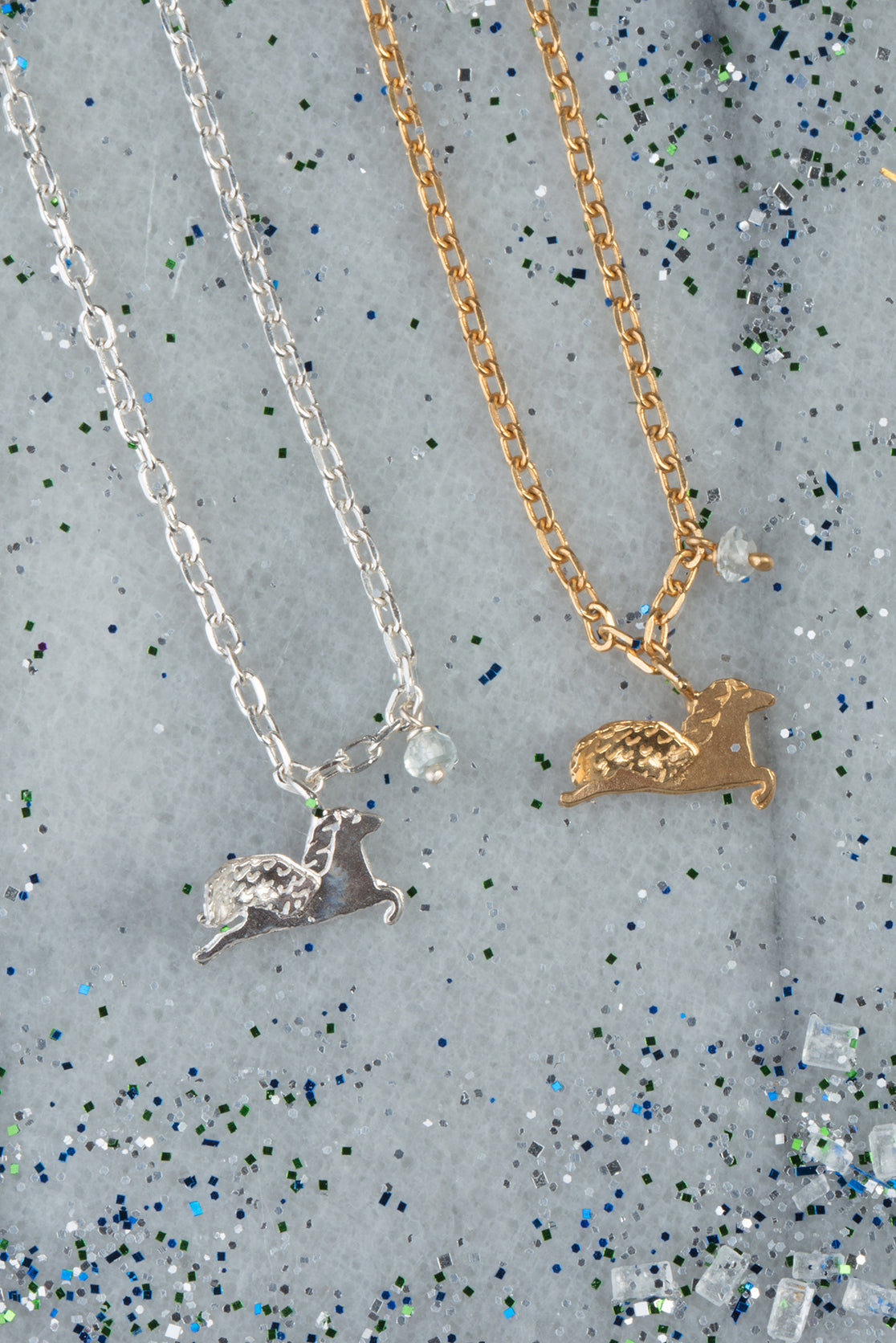 Dainty gold and sterling silver Pegasus necklace on grey glitter background 